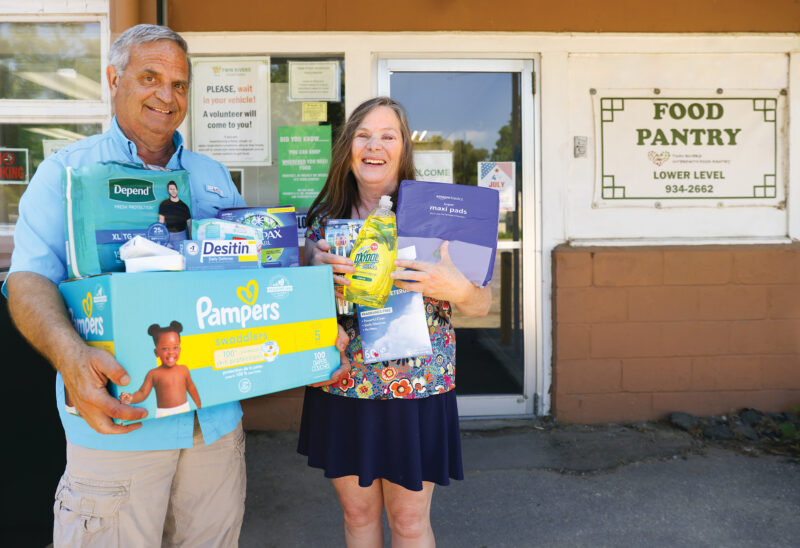 Twin Rivers Food Pantry Executive Director Alison Jones (right) and volunteer Brad Parker display some of the hygiene products available to clients. (Photo by Cheryl Senter)